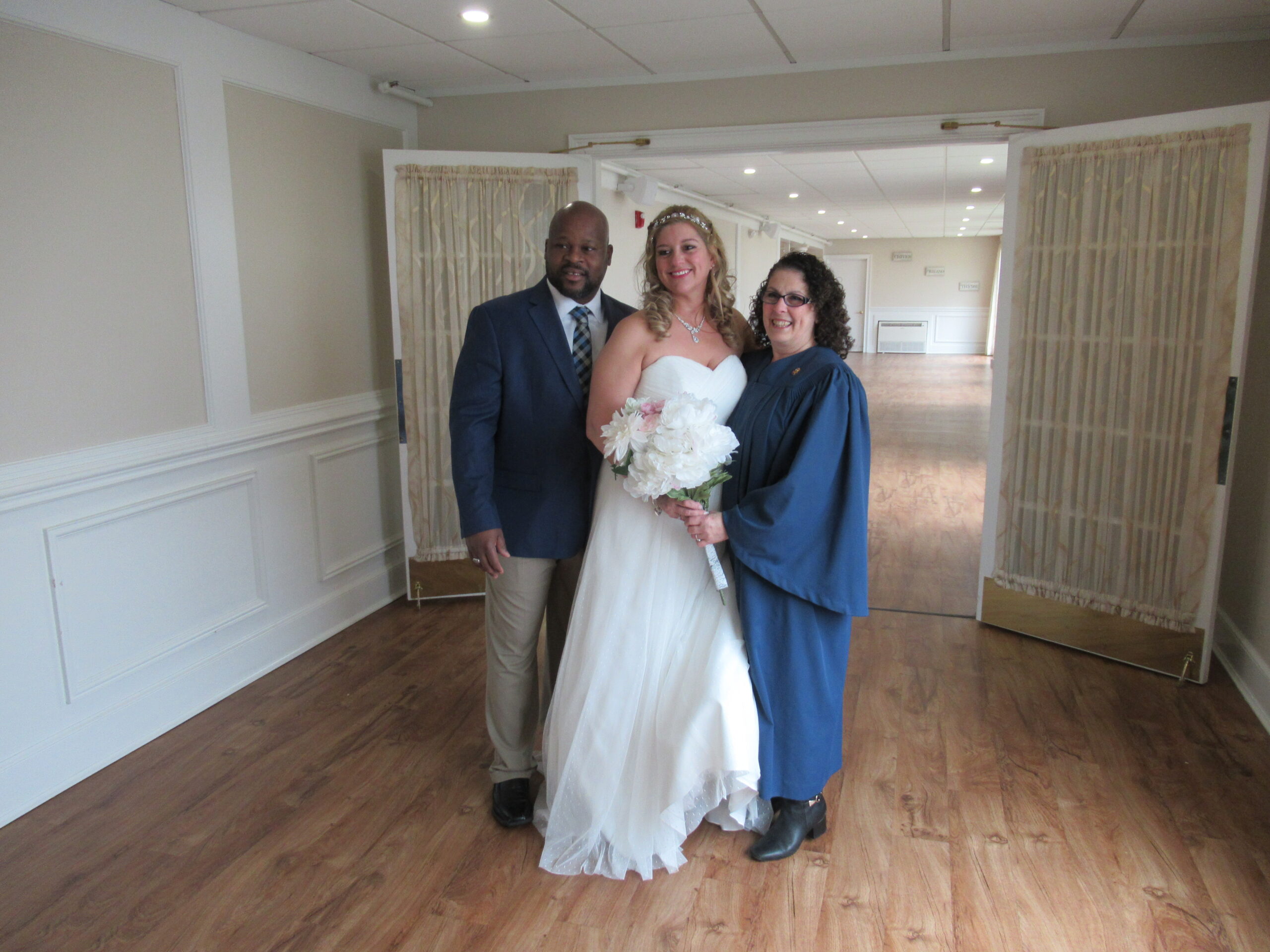 A newly wedded couple taking a picture with the presider of the event