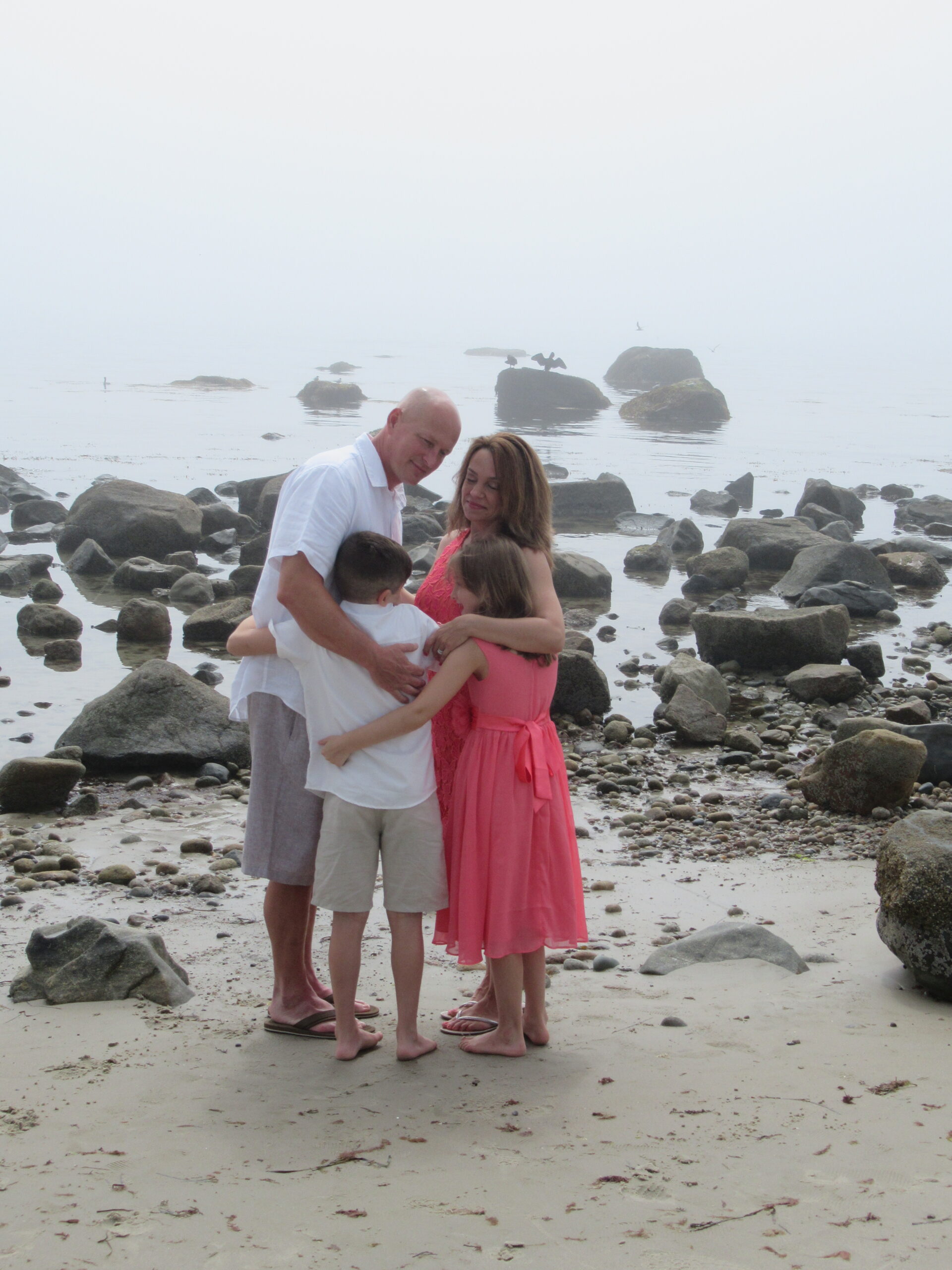 A family embracing each other on a rocky beach