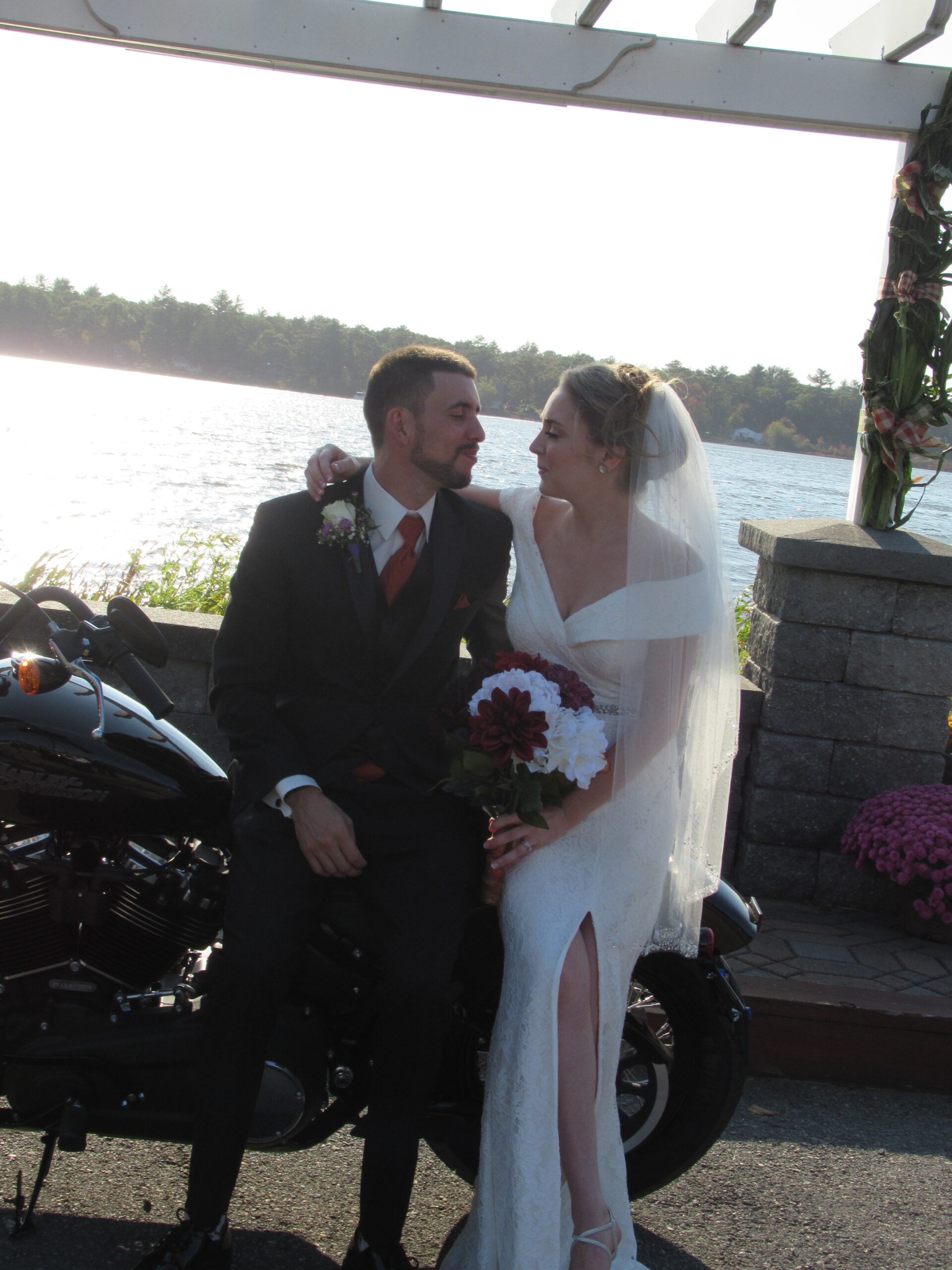 A newly wedded couple sitting on the back of a motorcycle